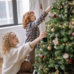 Mother and son are decorating a Christmas tree.