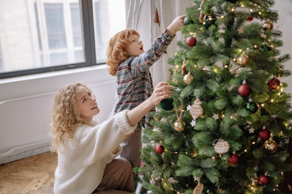 Mother and son are decorating a Christmas tree.